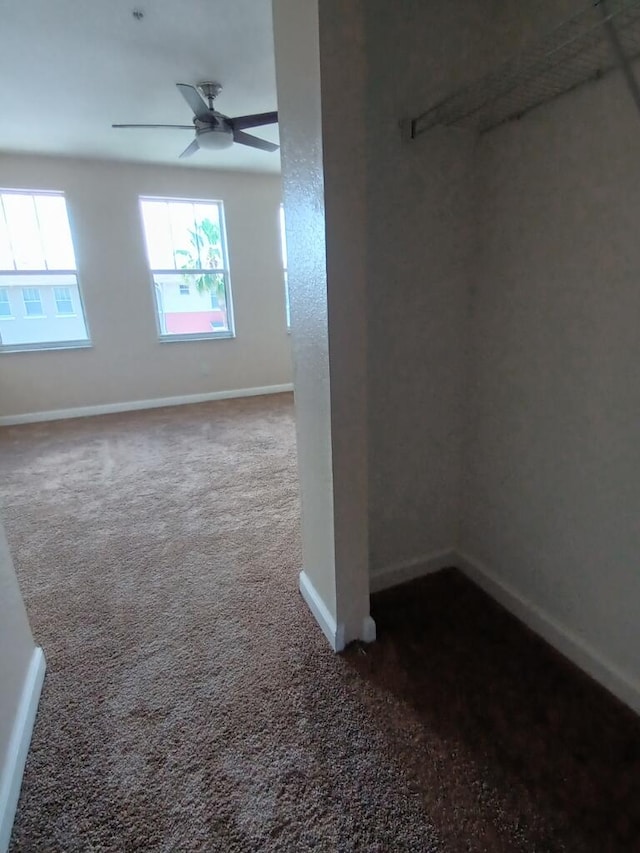 spare room with dark carpet and ceiling fan