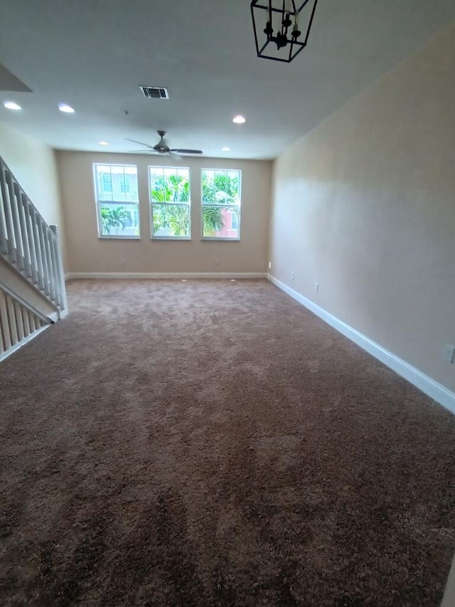 empty room featuring carpet and ceiling fan with notable chandelier