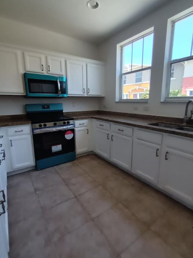 kitchen featuring white cabinets, electric stove, and a wealth of natural light