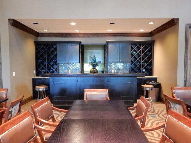 bar featuring blue cabinets, tasteful backsplash, and ornamental molding