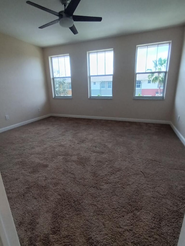 carpeted empty room featuring ceiling fan and a wealth of natural light