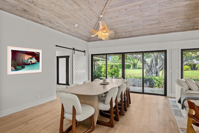 dining space with a barn door, vaulted ceiling, wooden ceiling, and light hardwood / wood-style floors