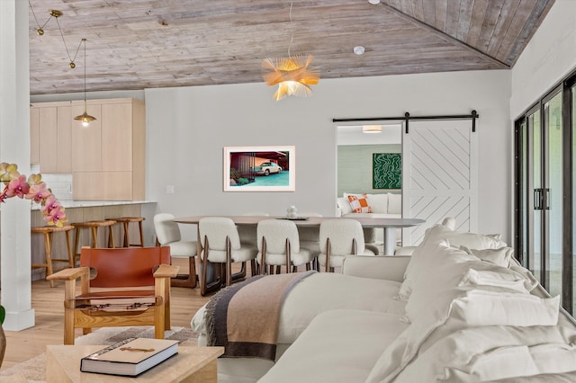 bedroom with wood ceiling, a barn door, vaulted ceiling, and light wood-type flooring