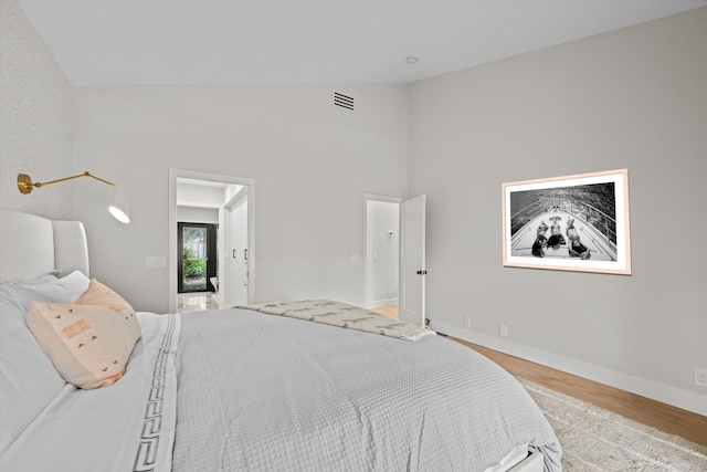 bedroom with light wood-type flooring and vaulted ceiling