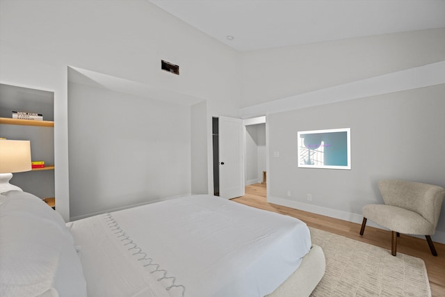 bedroom with light wood-type flooring and high vaulted ceiling