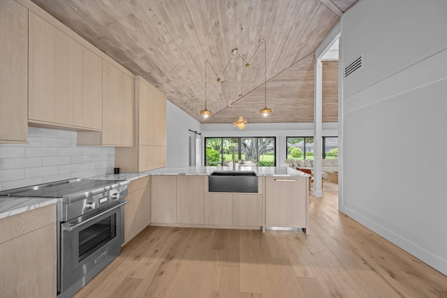 kitchen featuring high end range, light brown cabinetry, kitchen peninsula, sink, and light hardwood / wood-style floors