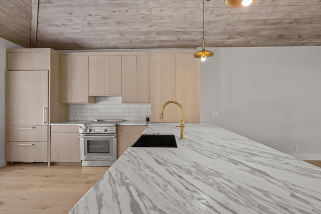 kitchen featuring pendant lighting, light brown cabinetry, light hardwood / wood-style flooring, sink, and electric stove