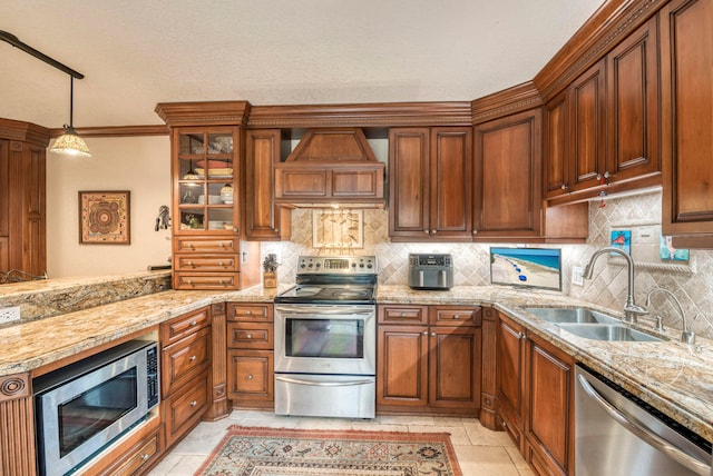 kitchen featuring pendant lighting, custom exhaust hood, crown molding, sink, and appliances with stainless steel finishes