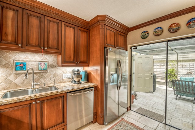 kitchen featuring crown molding, light stone counters, sink, and appliances with stainless steel finishes