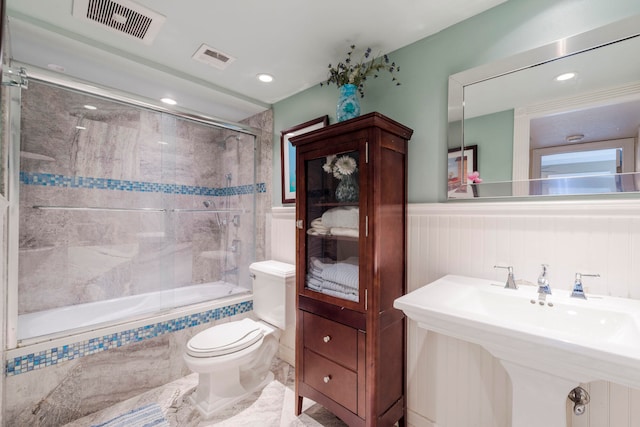 full bathroom with toilet, bath / shower combo with glass door, and sink