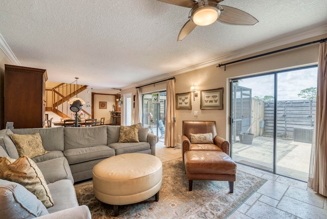 living room with ceiling fan, a textured ceiling, and ornamental molding