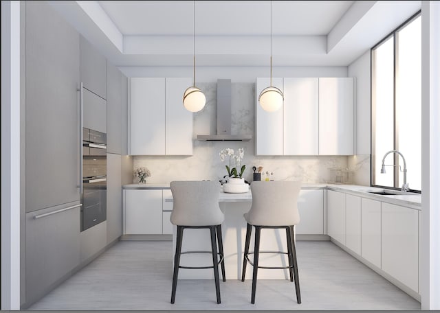 kitchen featuring sink, light hardwood / wood-style floors, wall chimney range hood, and decorative light fixtures