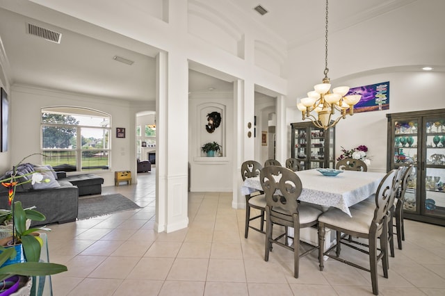 tiled dining room with ornamental molding, a notable chandelier, and a towering ceiling