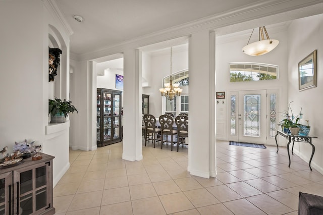 entryway with an inviting chandelier, ornamental molding, and light tile patterned floors