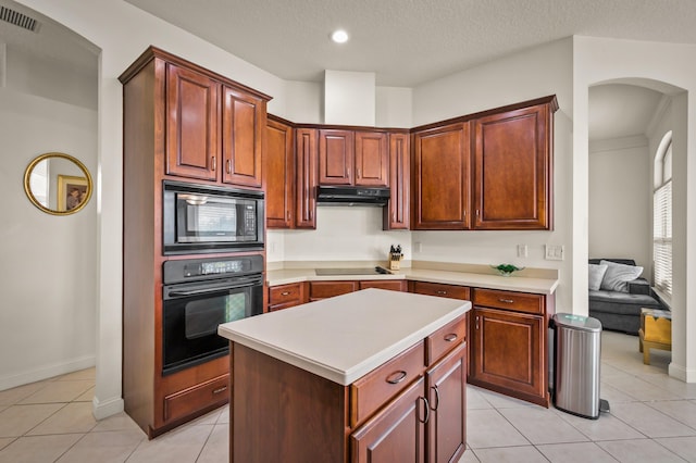 kitchen featuring extractor fan, stainless steel microwave, light tile patterned floors, a kitchen island, and black oven