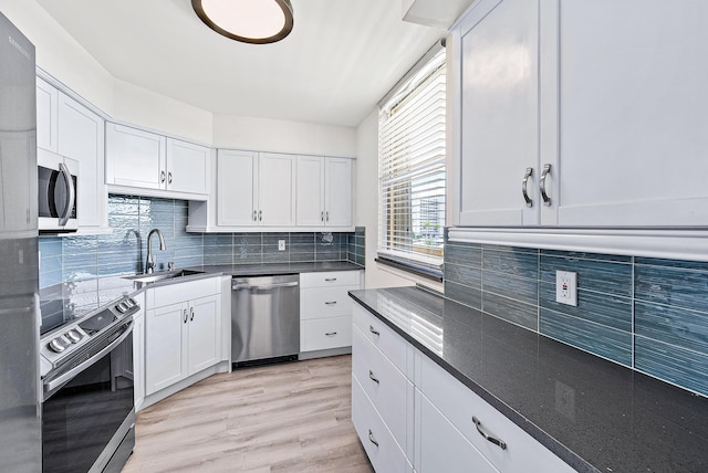 kitchen with appliances with stainless steel finishes, sink, light hardwood / wood-style flooring, white cabinetry, and tasteful backsplash