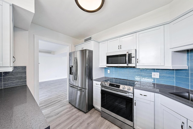 kitchen featuring appliances with stainless steel finishes, light wood-type flooring, backsplash, stone counters, and white cabinetry