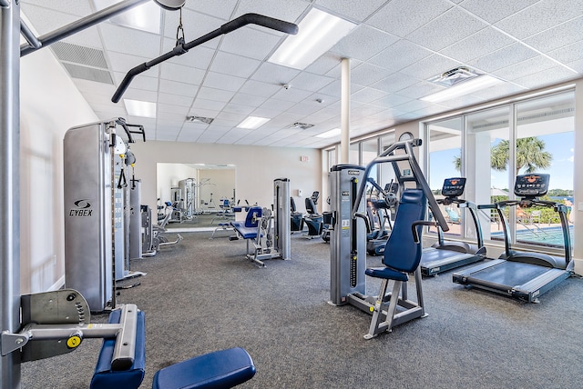 workout area featuring dark carpet and a drop ceiling