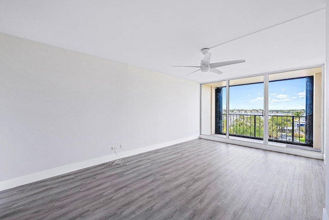 empty room with ceiling fan, hardwood / wood-style flooring, and floor to ceiling windows