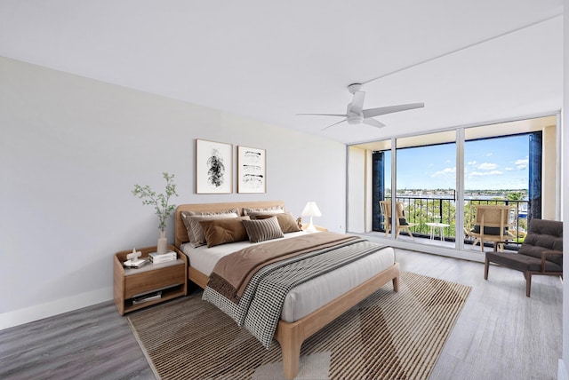 bedroom with ceiling fan, access to exterior, light hardwood / wood-style floors, and a wall of windows