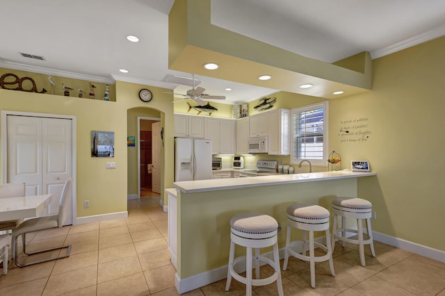 kitchen with white appliances, kitchen peninsula, ceiling fan, and light tile floors