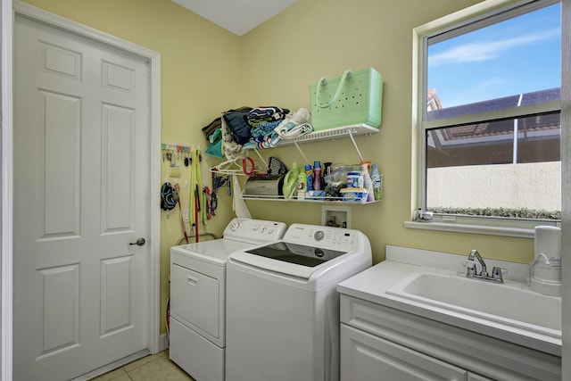 washroom with sink, washer and dryer, a healthy amount of sunlight, and light tile flooring