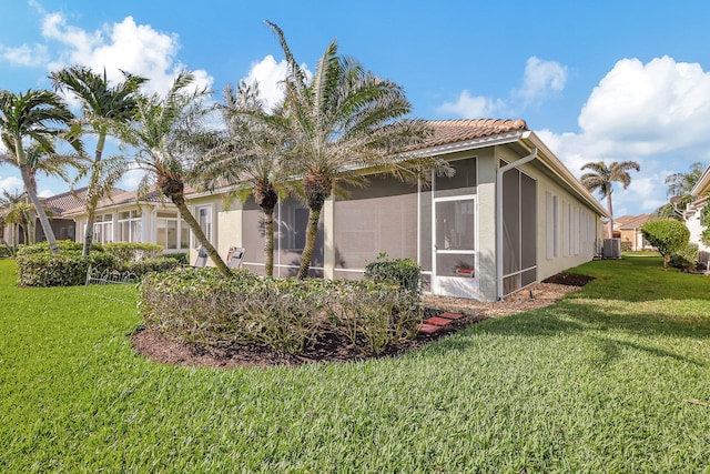 view of side of home featuring a yard, central air condition unit, and a sunroom