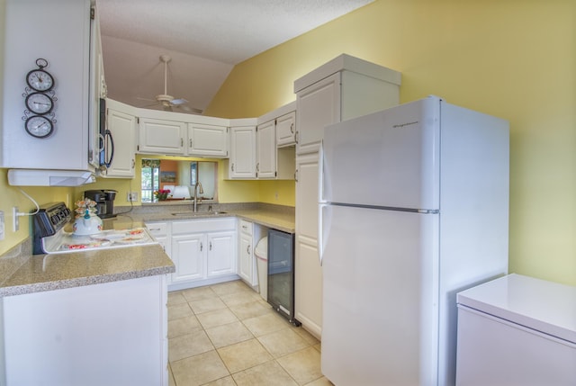 kitchen with ceiling fan, sink, white refrigerator, range, and vaulted ceiling