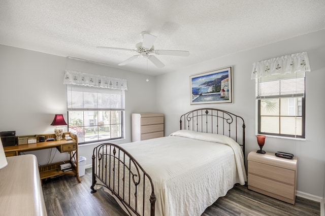 bedroom with dark wood-style floors, multiple windows, a textured ceiling, and baseboards