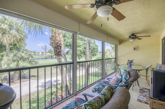 sunroom featuring ceiling fan and a water view