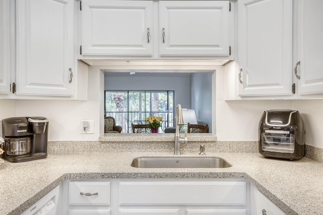 kitchen featuring a sink, white cabinets, light countertops, and white dishwasher