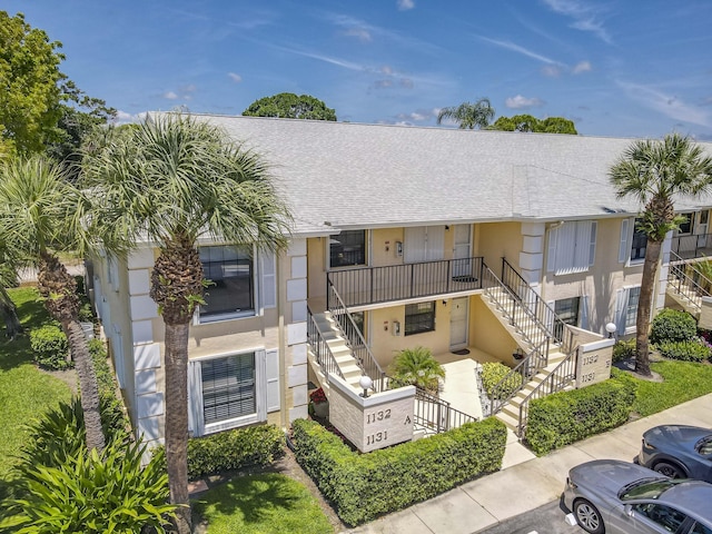 view of property featuring stairway and uncovered parking