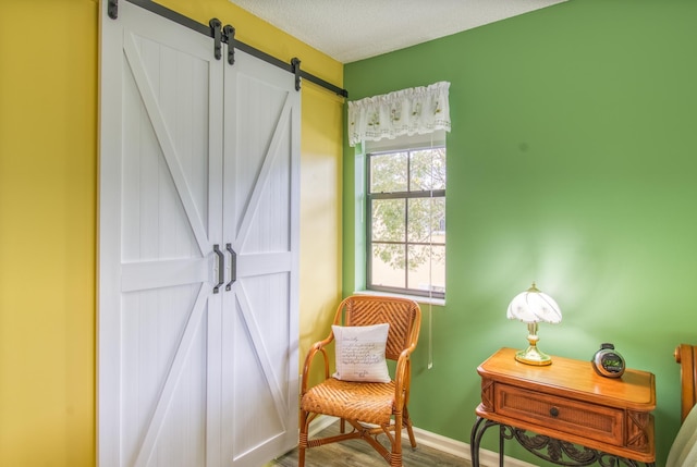 living area with a barn door, hardwood / wood-style floors, and a textured ceiling