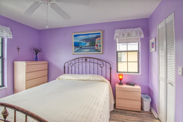 bedroom with a closet, a textured ceiling, ceiling fan, and dark hardwood / wood-style flooring