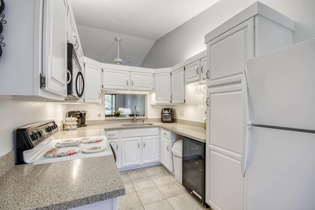 kitchen featuring electric range, freestanding refrigerator, a sink, wine cooler, and vaulted ceiling