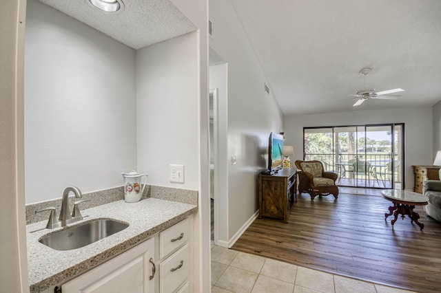 bathroom featuring tile patterned flooring, ceiling fan, a textured ceiling, vanity, and baseboards