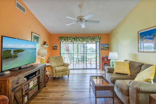 living room featuring vaulted ceiling, a textured ceiling, ceiling fan, and light wood-type flooring