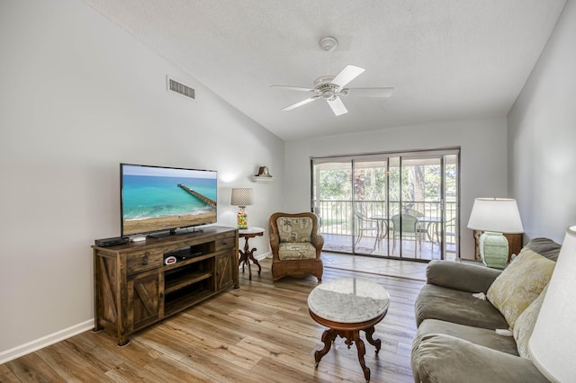 living area with lofted ceiling, light wood-style flooring, a ceiling fan, a textured ceiling, and baseboards