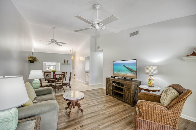 living room featuring a ceiling fan, vaulted ceiling, light wood-type flooring, and baseboards