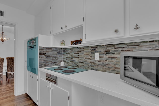 kitchen featuring a chandelier, light hardwood / wood-style flooring, black appliances, white cabinetry, and backsplash