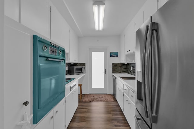 kitchen with appliances with stainless steel finishes, white cabinetry, tasteful backsplash, and dark wood-type flooring