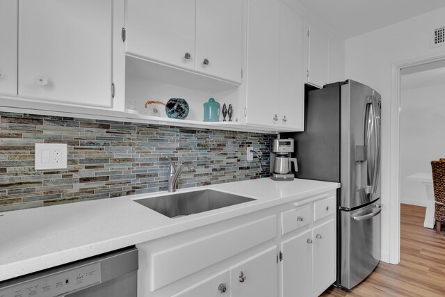 kitchen featuring tasteful backsplash, light hardwood / wood-style flooring, dishwasher, and white cabinetry