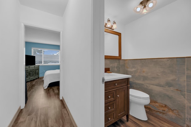 bathroom with tile walls, toilet, vanity, and hardwood / wood-style flooring