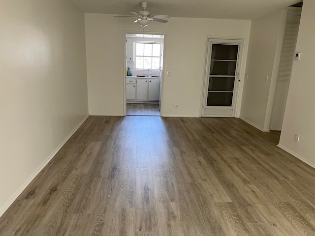 empty room featuring wood-type flooring, ceiling fan, and sink