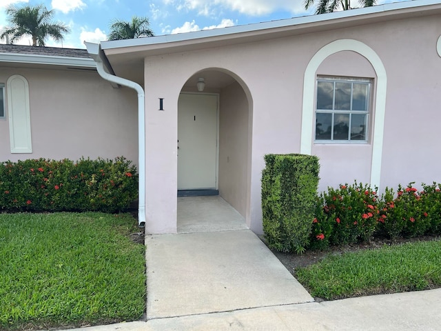 property entrance with a lawn