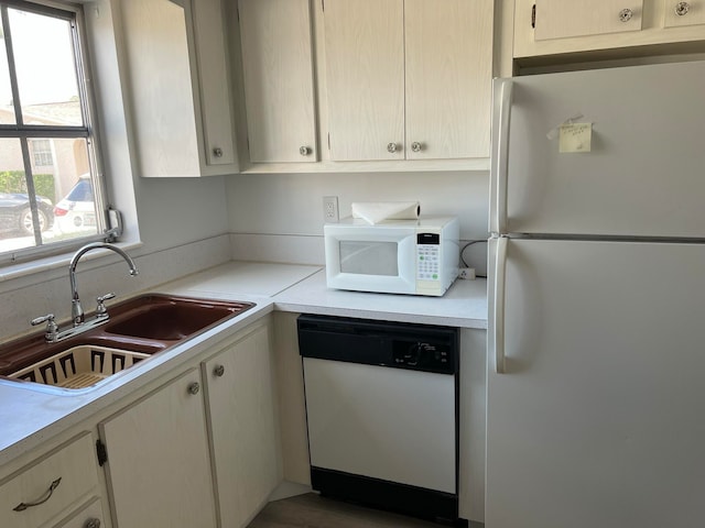 kitchen with white appliances, hardwood / wood-style flooring, and sink