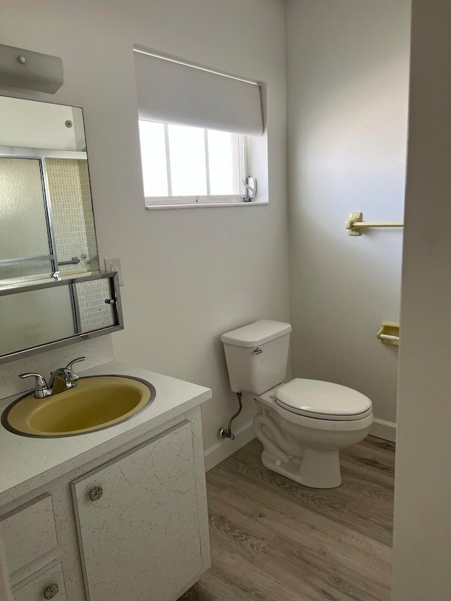 bathroom with toilet, vanity, and wood-type flooring