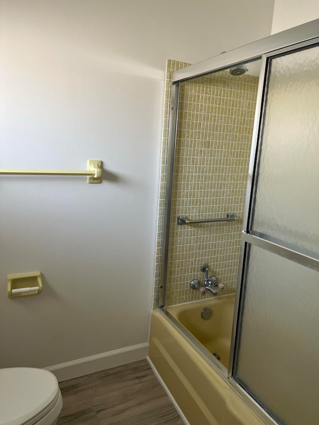 bathroom featuring combined bath / shower with glass door, toilet, and wood-type flooring