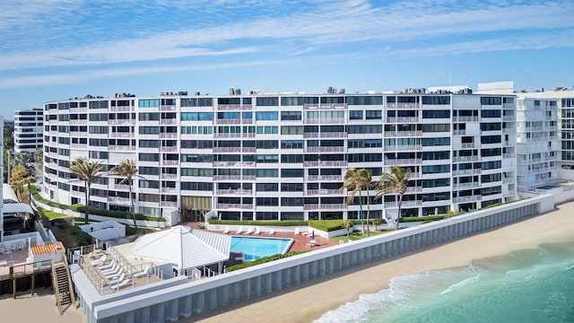 view of building exterior with a view of the beach, a water view, and a community pool