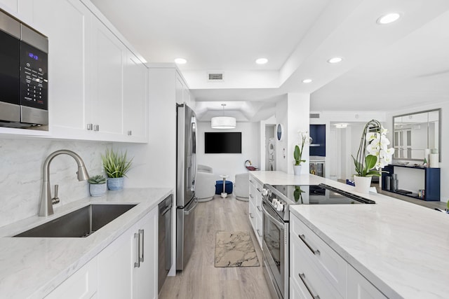 kitchen featuring appliances with stainless steel finishes, sink, light stone counters, and white cabinets